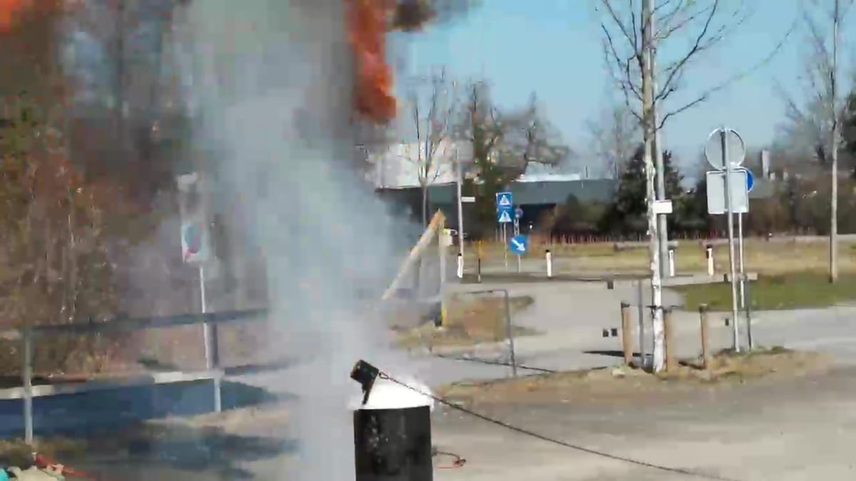 Standbild: Feuerschale auf einem Übungsplatz, aus der eine Stichflamme mit Rauch schlägt